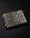 Mozane No. 1, embossed silver-tone metal case on a dark background